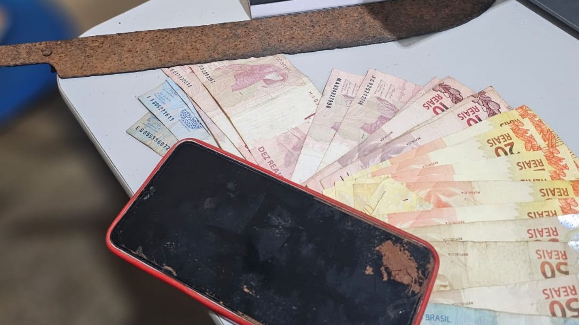 Dinheiro, celular e a faca apreendida na ação. (Reprodução, PMMS)